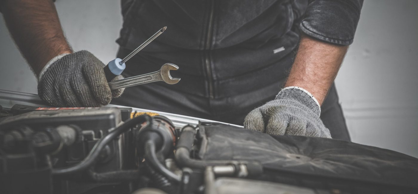 Car mechanic looking to the engine in the garage. Car motor repair. Problems and solutions concept.